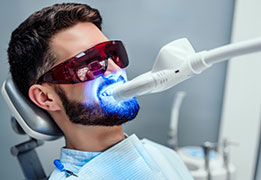 Closeup view of a man undergoing laser tooth whitening treatment to remove stains and discoloration.