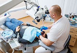 The dentist treats his patient's teeth with a microscope. The dentist treats the patient's mouth. Dental care. High-quality photo